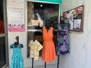 Store front of Global Mamas displaying garments on mannequins. 