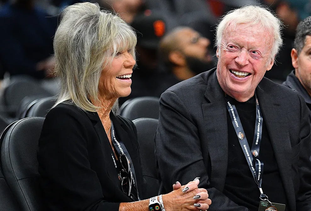Penny Knight and Phil Knight sitting down and exchanging laughs. 
